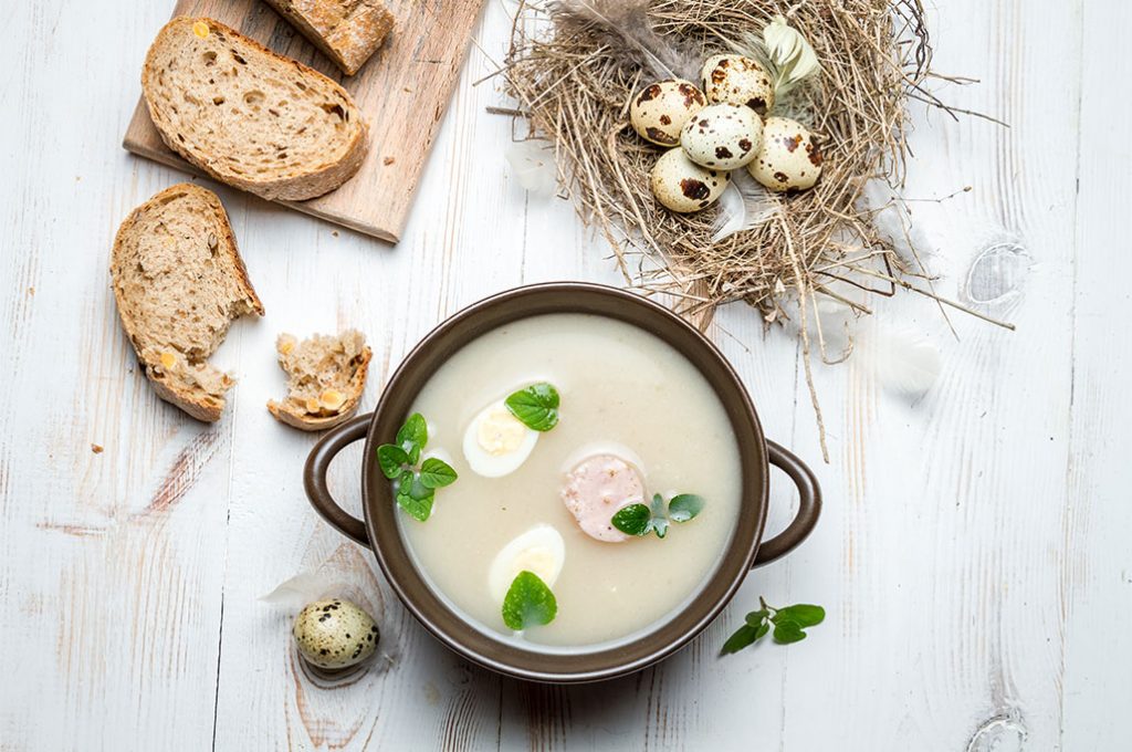 home-slider-img4 Wielkanocny barszcz biały z jajkami i kiełbasą w misce, podawany z pieczywem i jajami przepiórczymi.